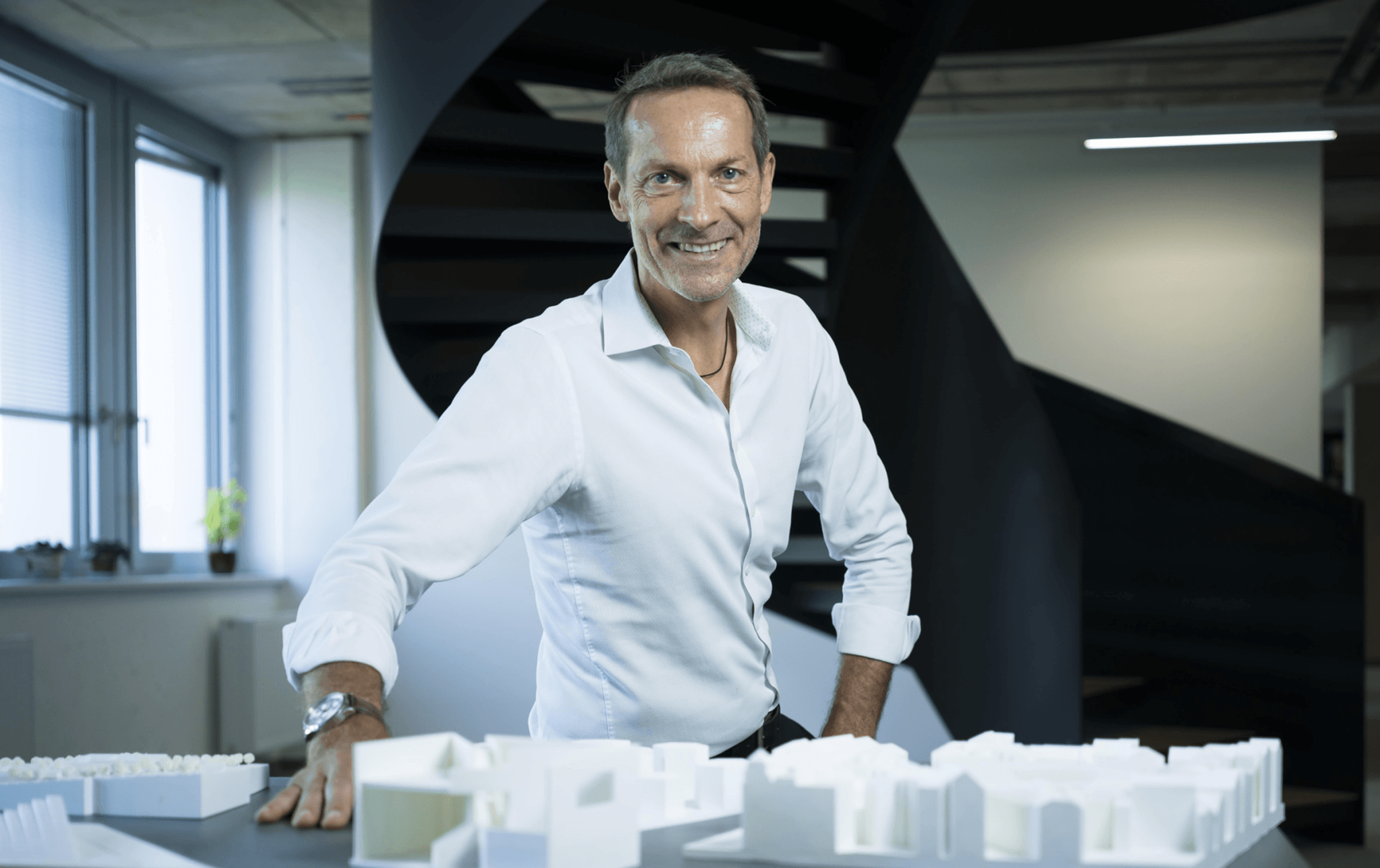 Architekt präsentiert Architekturmodell in modernem Büro mit Treppe